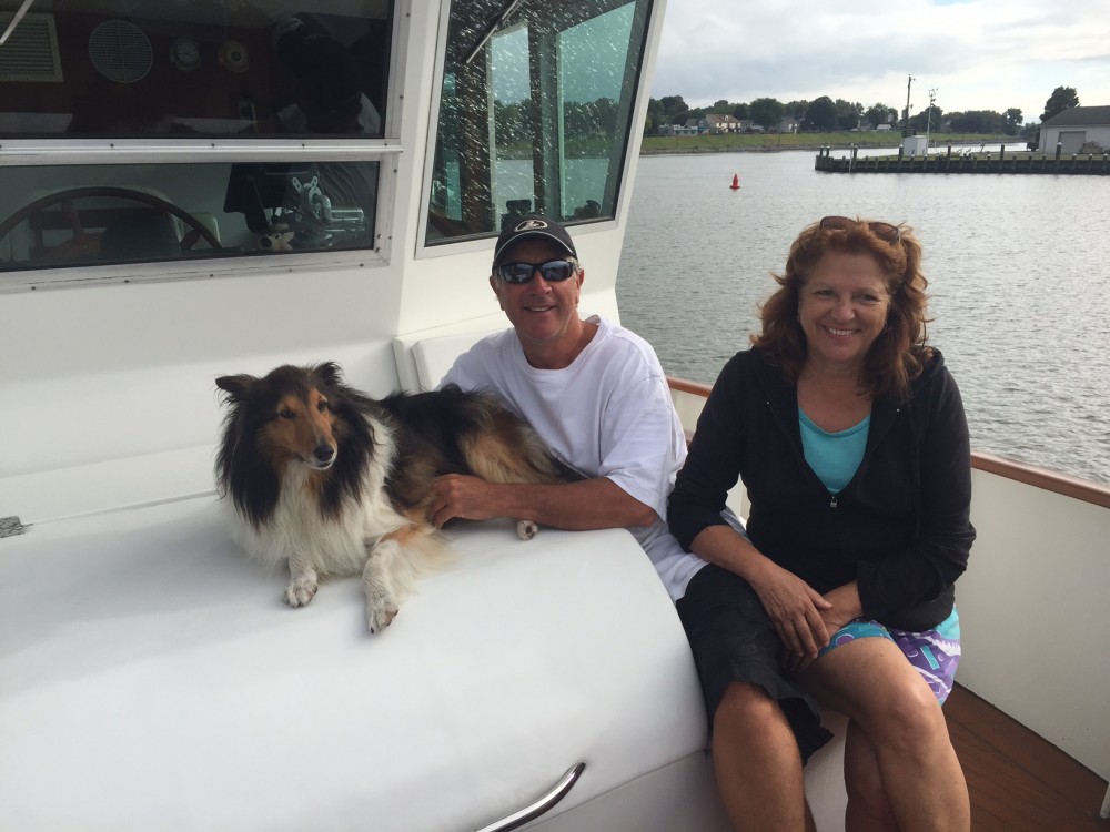 Smiling couple on their boat with their dog